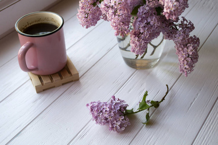 白色木桌上一杯咖啡和丁香花..