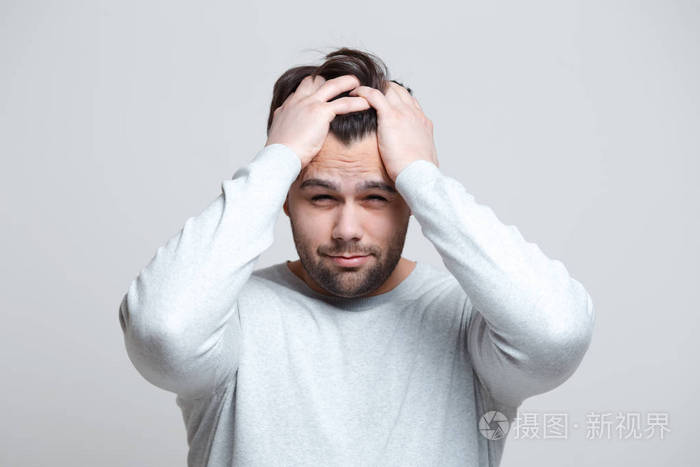 年轻人头痛的肖像双手托着头白色