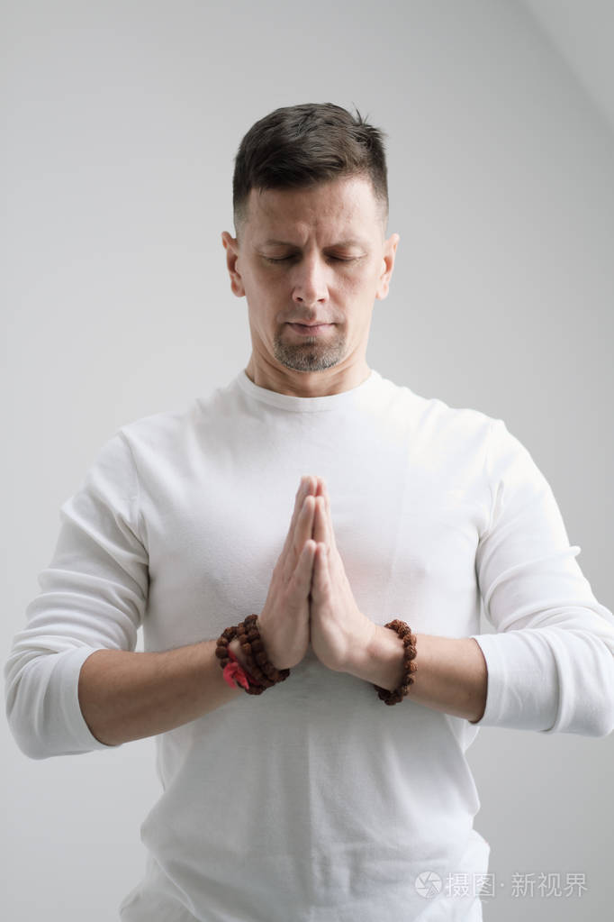 一名身穿白色衣服的男子双手合拢在胸前, 身穿白色背景.