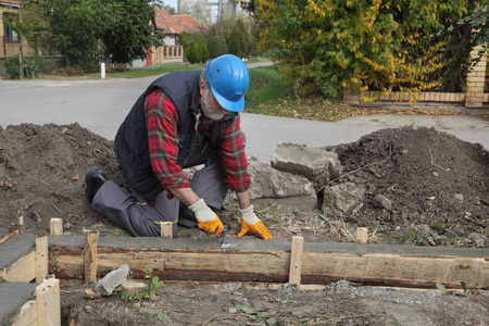 工人在墙基础模板上铺混凝土，用铲子，真人工作