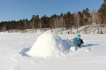 穿着温暖衣服的幸福女人在冬天的西伯利亚俄罗斯雪坡上建了一个冰屋
