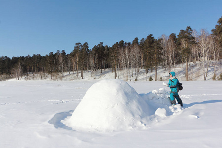穿着温暖衣服的幸福女人在冬天的西伯利亚俄罗斯雪坡上建了一个冰屋