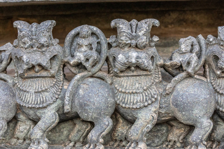 印度卡纳塔克邦Halebidu2013年11月2日希瓦霍伊萨莱斯瓦拉神庙。 寺庙结构侧面的狮子雕像特写，灰色的石头和一些棕色的