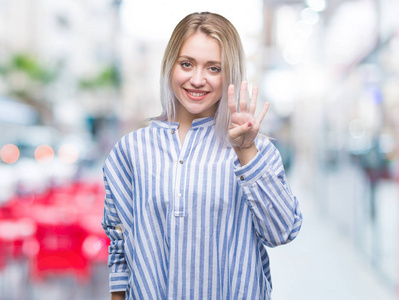 年轻的金发女子在孤立的背景显示和指着第四个手指，同时微笑自信和快乐。