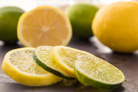 新鲜柠檬和石灰片的近距离视图设置在整个和切片水果前面。