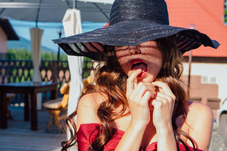 美丽的年轻女子在红色礼服和巴拉克帽子在夏天阳光明媚的日子