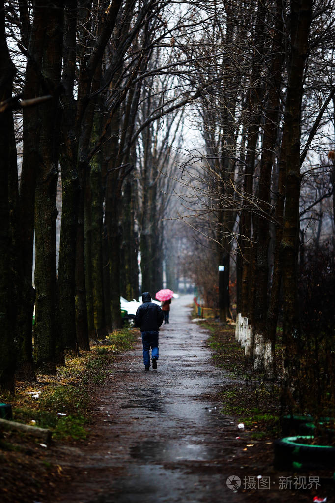 一个人在雨中带着雨伞沿着路走
