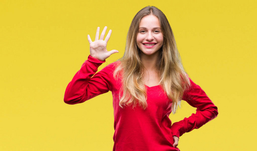 年轻漂亮的金发女人穿着红色毛衣，在孤立的背景上，用手指举着第五个，同时微笑着自信和快乐。