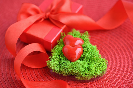 情人节背景。 绿色苔藓和红色礼盒的心