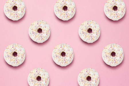 粉红色背景上的新鲜美味甜甜甜圈。 快餐烘焙早餐糖果的概念。 极简主义。 模式。 平躺式顶部视图