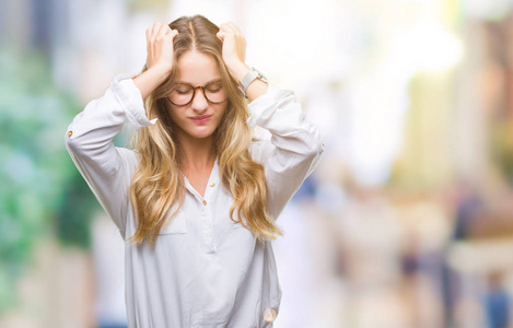 年轻漂亮的金发商务女性戴着眼镜，在孤立的背景下，因疼痛和偏头痛而感到头痛绝望和压力。 手放在头上。