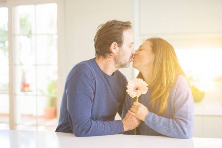 浪漫的中年夫妇捧着鲜花在家里接吻