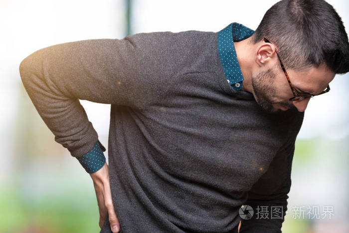 年轻的帅哥戴着眼镜在孤立的背景下背部疼痛手肌肉疼痛