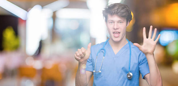 年轻的医生穿着医疗制服，在孤立的背景上显示和举着手指第六，同时微笑自信和快乐。