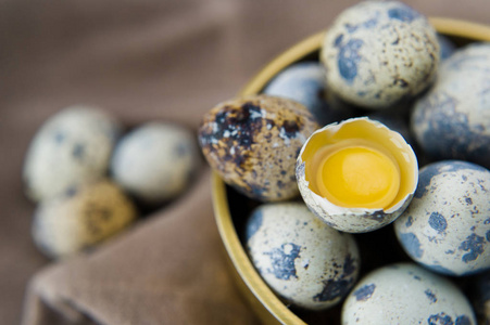 金碗里的鹌鹑蛋，一个破碎的鸡蛋。 白色背景顶部视图关闭