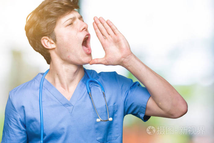 年轻的医生穿着医疗制服在孤立的背景上大声喊叫和尖叫手在嘴上交流