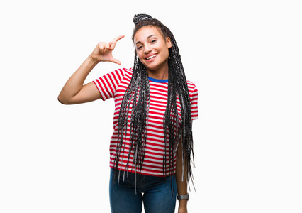 年轻的辫子非裔美国女孩在孤立的背景上微笑和自信的手势与手做大小标志与手指，同时看和相机。 测量概念。