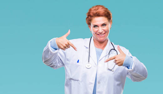 高级白种人医生女士穿着医疗制服，背景偏僻，看上去自信，脸上带着微笑，用手指指着自己，骄傲和快乐。