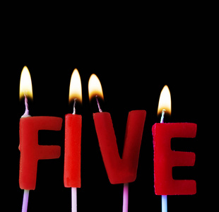 五支红色生日蜡烛在黑色背景下拼出