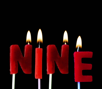 九支红色生日蜡烛在黑色背景下拼出的咒语