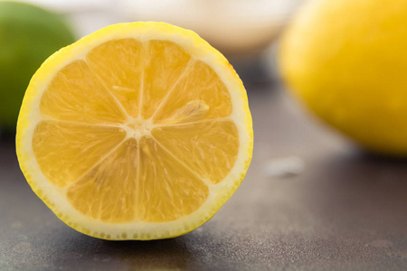 一个新切片柠檬的近景。背景中的焦点是更新鲜的整体水果，用一小碗糖做新鲜的柠檬水。