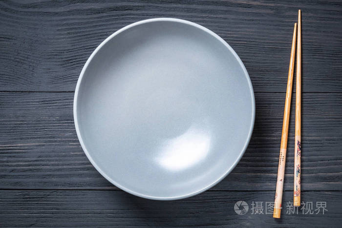 空碗泡面用筷子夹在黑色木制背景上有一个复制空间的地方
