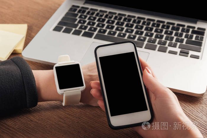 带有笔记本电脑,智能手机和空白屏幕的女性部分视图
