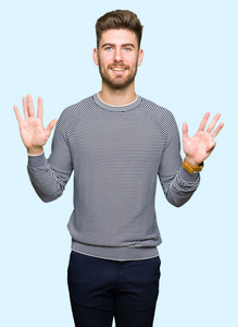 年轻英俊的男人穿着条纹毛衣，用手指举着九号，微笑着自信和快乐。