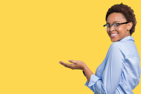 年轻美丽的非裔美国商务女性，在孤立的背景下，用手和张开的手掌指向一边，呈现出微笑快乐和自信的广告