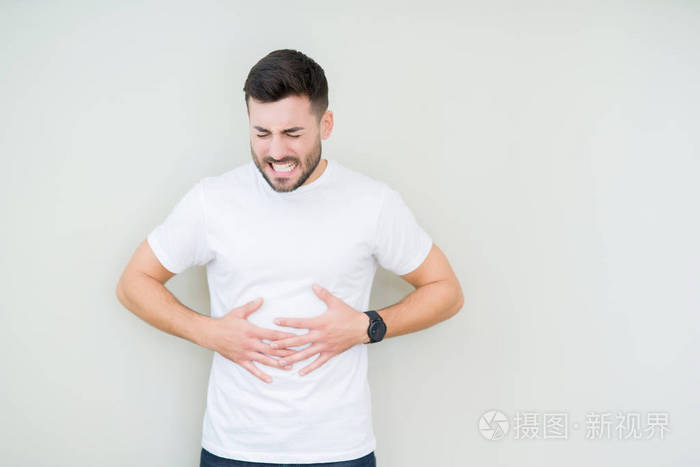 年轻英俊的男人穿着休闲的白色t恤,在孤立的背景上,手放在肚子上,因为