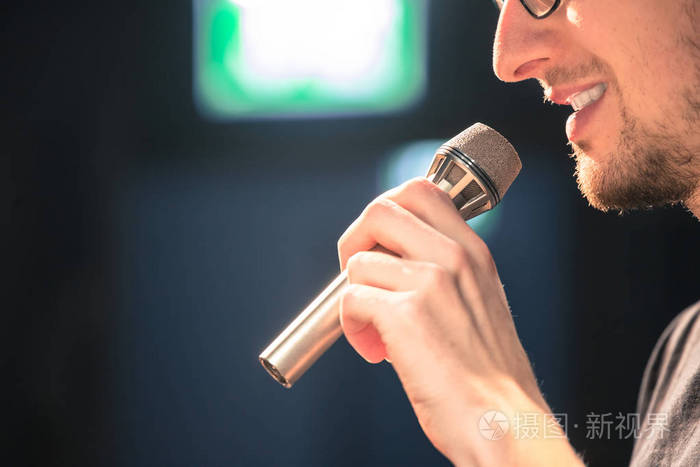 舞台上的年轻人正在对着麦克风讲话