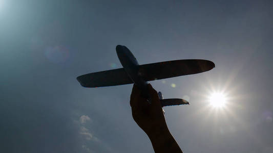 一架模型飞机在阳光明媚的天空中的剪影。 旅行和运输的概念。 梦想假期