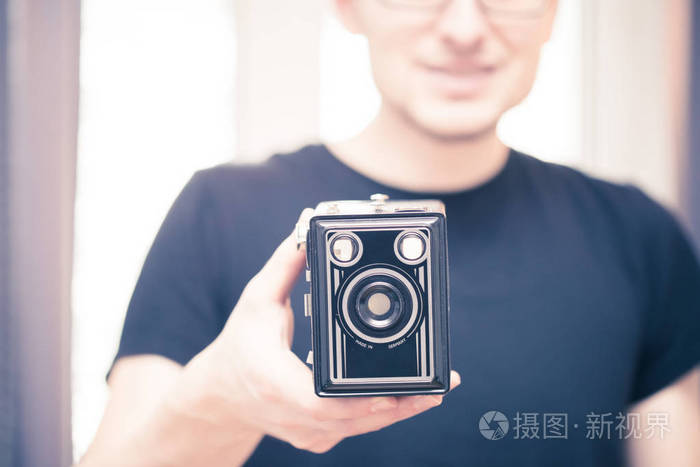 身穿黑色衬衫的年轻人正在用黑色德国老式相机拍照