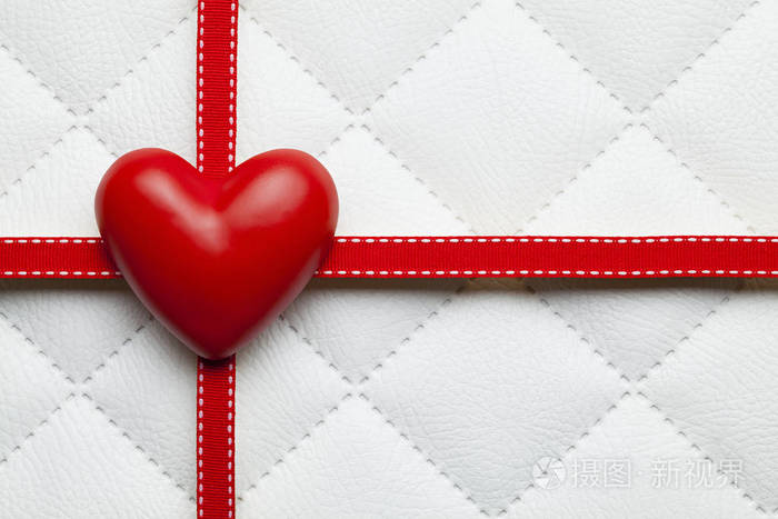 红色的心和白色被子皮革背景上的丝带