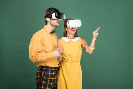 兴奋的夫妇，老式的衣服和虚拟现实耳机隔离在绿色上