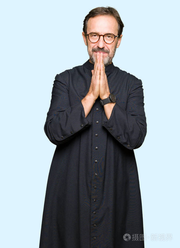 中年牧师穿着天主教长袍双手祈祷请求宽恕微笑自信