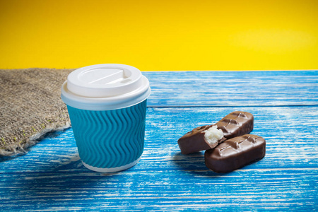 蓝色一次性杯子，木制背景上有香味的咖啡，靠近精制糖