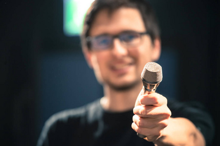 舞台上的年轻人正对着麦克风说话,说话的脸很模糊照片