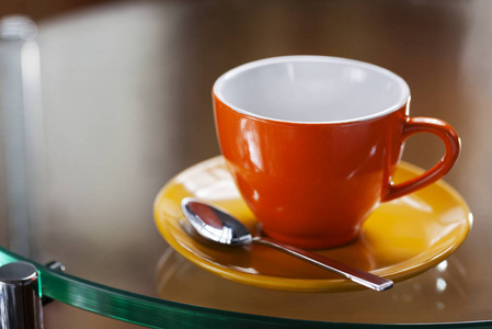 玻璃桌上一个空的彩色杯子和茶托上一个漂亮的窗户反射