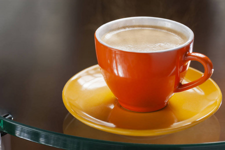 在一杯五颜六色的热咖啡中，玻璃桌上放着奶油色的漂亮的窗户反射