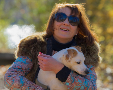 一位40岁的秋天公园里带着一只狗度假的女人的肖像。