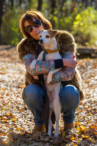一个女人带着一只狗在秋天公园度假的肖像，年龄40岁