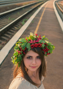 一个女孩的肖像，头上戴着花环，背景是铁路