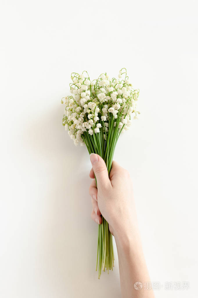 妇女手拿着山谷中的百合花花束