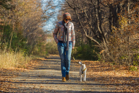 在秋天公园和一只狗散步的女人，40岁