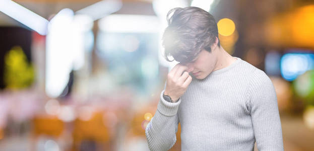 年轻的帅哥穿着冬天的毛衣，在孤立的背景下疲惫地鼻子和眼睛，感到疲劳和头痛。 压力和挫折的概念。