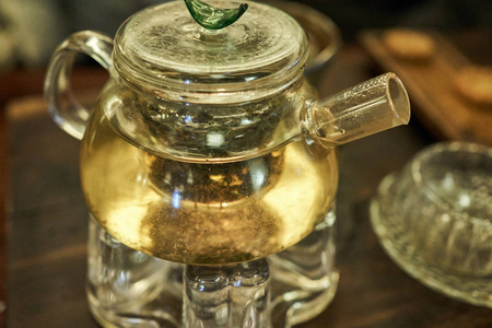 一个透明的茶壶在黄色的发光，因为火在下面点燃，以保持锅的温暖。
