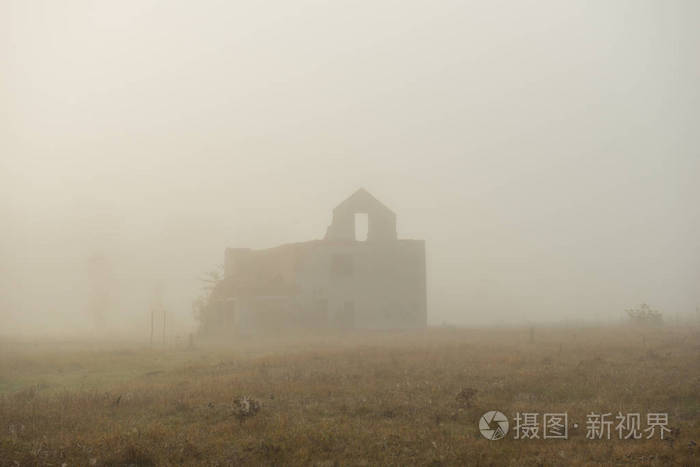 雾中荒芜的旧房子的乡村景观