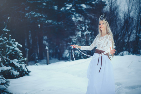 冬天美女。 美丽的时尚模特女孩，在冬天的森林里在冬季森林。 节日化妆和美甲。 有冰雪发型的冬季女王。 魔法