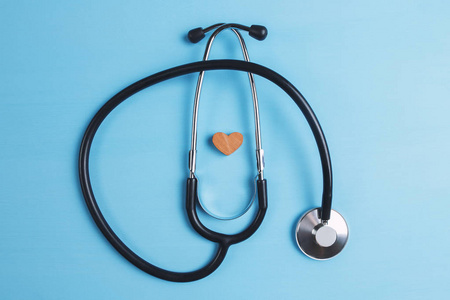 听诊器和蓝色背景上的木制心脏